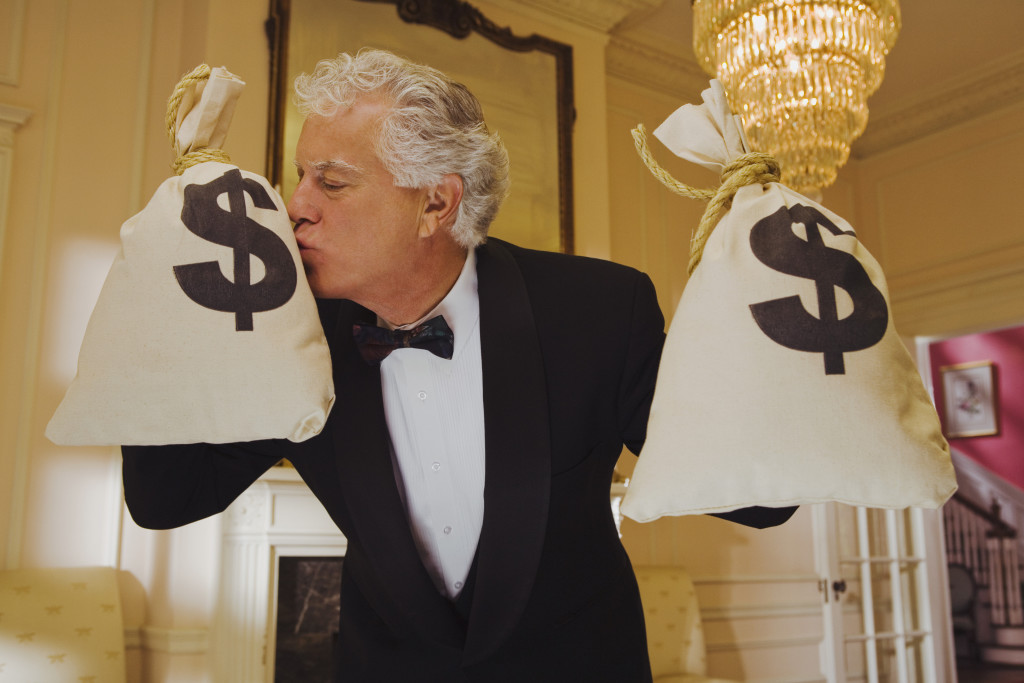 Wealthy man kissing money bags