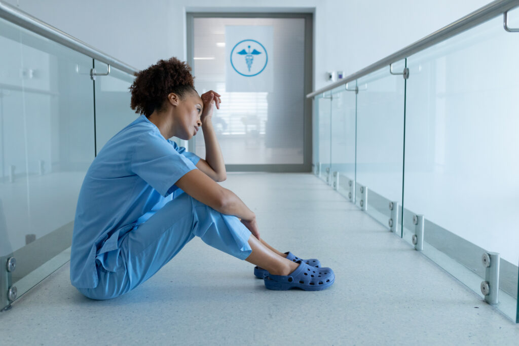 African american female doctor sitting in hospital corridor taking rest